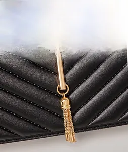 Close-up of black V-quilted leather texture with elegant gold tassel hardware detail
