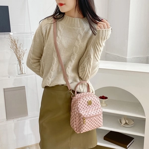 Pink mini backpack with geometric pattern and golden zipper in a minimalist interior