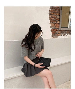 Foto lifestyle all'aperto di una pochette trapuntata nera con cinturino da polso