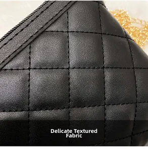 Close-up of black quilted leather texture with gold chain strap and zipper detail
