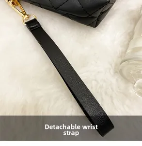 Detail of detachable black leather wrist strap with gold metal clasp on quilted bag