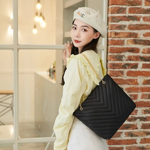 Sac à bandoulière matelassé noir avec chaîne dorée porté par un mannequin dans un décor urbain