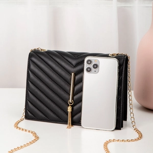 Quilted black crossbody bag with gold tassel, chain strap and mobile phone for size scale