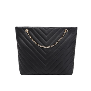 Sac cabas noir matelassé en V avec bandoulière chaîne dorée sur fond blanc neutre