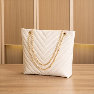 Detail of cream V-quilted texture and gold chain strap on a chic crossbody tote bag