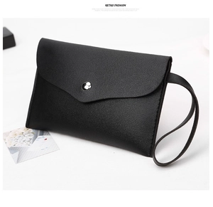 Macro detail of black nappa grain leather clutch bag with silver snap button and wristlet