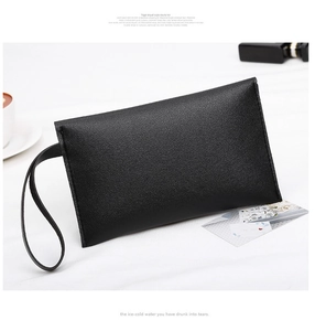 Detail of black pebbled leather envelope clutch bag showing fine lychee texture and wristlet