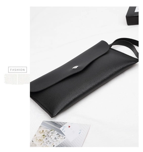 Detail of minimalist black faux leather pouch with silver metal button and hand strap