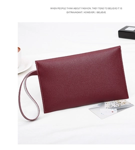 Close-up of burgundy lychee grain leather clutch bag with matching wrist strap
