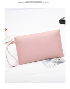 Pink nappa texture envelope clutch bag with wristlet strap shown on a minimalist desk