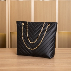 Detail of black V-quilted faux leather tote bag with elegant gold chain strap