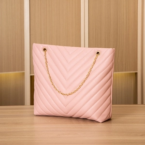 Detail of pink quilted tote bag with V-shaped embroidery and golden chain handle