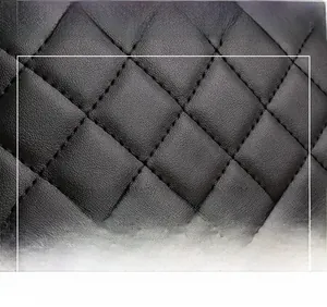 Close-up of black quilted faux leather fabric with precise stitching and lychee grain texture