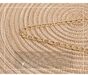 Detailed close-up of a high-quality shiny gold metal chain on a woven straw mat texture