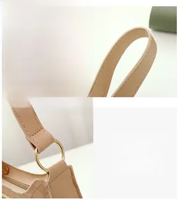Close-up of beige shoulder bag showing fine stitching and gold circular hardware