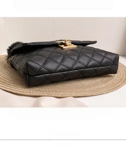 Detail of black quilted shoulder bag with faux fur trim and gold-tone square clasp