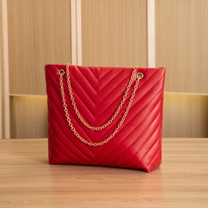 Detail of red leather tote featuring gold chain straps and V-shaped chevron quilting