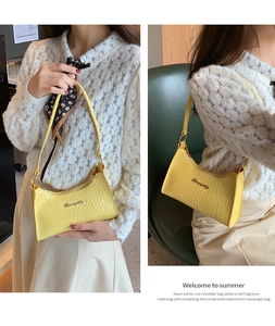 Detail of yellow crocodile pattern hobo bag with metal logo and floral scarf accent