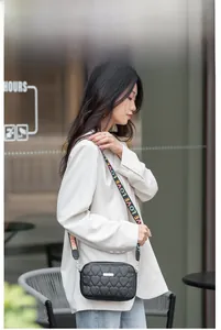 Detail of heart-quilted crossbody bag with colorful LOVE embroidered strap and metal tag