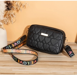 Detail of heart quilted black crossbody bag with LOVE lettered wide colorful strap