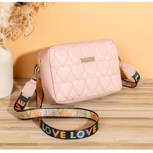 Detailed view of pink heart quilted bag with colorful LOVE woven shoulder strap