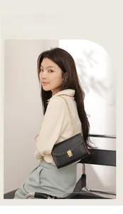 Close-up of black leather crossbody bag featuring gold rivet trim and chain strap