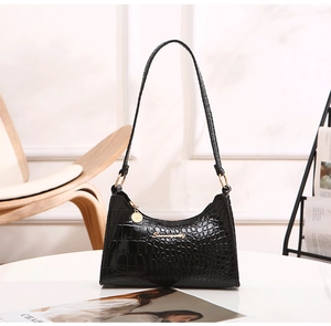 Detail of black crocodile embossed leather hobo bag with gold hardware and logo