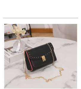 Detail view of 19x12x7cm black crossbody bag with red edges and gold rivet trim