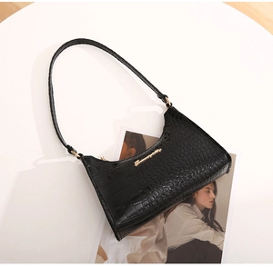 Detail of black crocodile pattern faux leather on hobo bag with gold metal hardware
