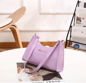 Detail of purple croc-embossed HOBO bag with gold logo on a white table setting