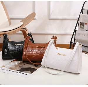 Detailed macro view of minimalist hobo bags in black, brown and white croc-embossed leather