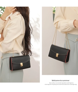 Close-up of black leather crossbody bag with gold stud rivets and chain strap