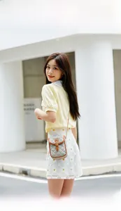 Gray quilted crossbody phone bag with brown leather trim shown on model outdoors