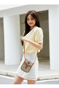 Close-up of quilted grey crossbody bag with contrast brown leather flap and pin buckle