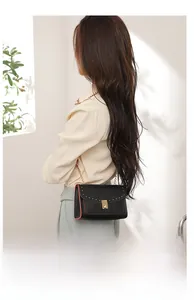 Close-up of black PU leather shoulder bag featuring metal rivets and golden chain strap