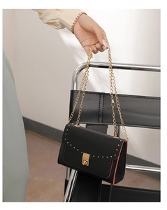 Close-up of black crossbody bag with gold stud trim and red edge paint detail