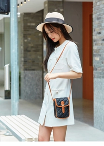 Close-up of quilted black crossbody phone bag with brown leather trim on a female model