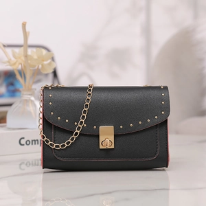 Detail of black crossbody bag with red edges, gold studs, and textured lychee leather