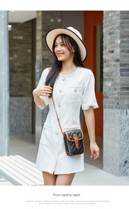 Black quilted phone bag with brown leather trim and golden buckle worn by a model