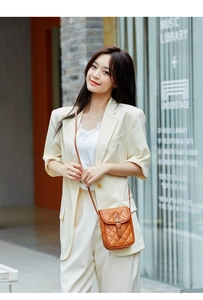Detail of a brown quilted crossbody phone bag with vintage buckle on a stylish model