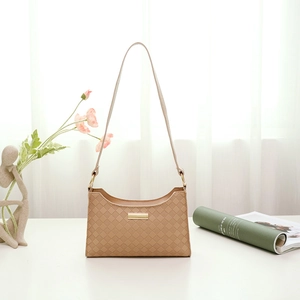 Elegant beige embossed shoulder bag for women with gold metal plaque on a white table