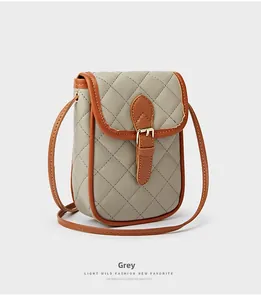 Macro shot of grey quilted phone bag with brown leather trim and golden metal buckle