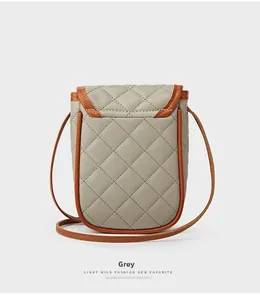 Detailed view of quilted grey crossbody bag with brown leather trim and contrast stitching