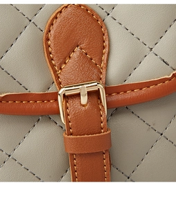 Detail of rhombic quilted grey faux leather with brown trim and metallic buckle clasp
