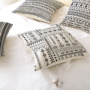 Set of four black geometric tribal pattern throw pillow covers on white linen bedding