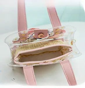Close-up of daisy print PVC tote bag with pink leather handle and straw inner pouch