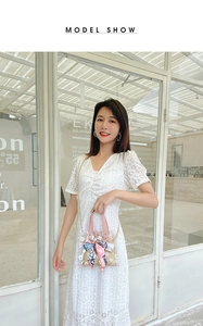 Detail of transparent daisy handbag with pink handles and a silk scarf on a white lace dress
