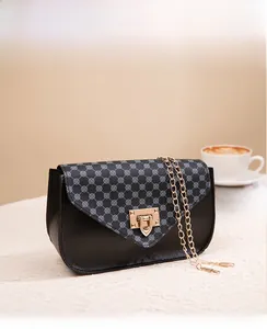 Detail of printed crossbody bag with golden twist lock and chain strap on a textured surface