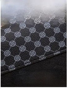 Macro shot of durable black litchi grain leather with grey four-leaf clover floral print