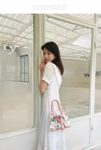 Detail of transparent PVC daisy bag featuring pink handles and a floral ribbon strap